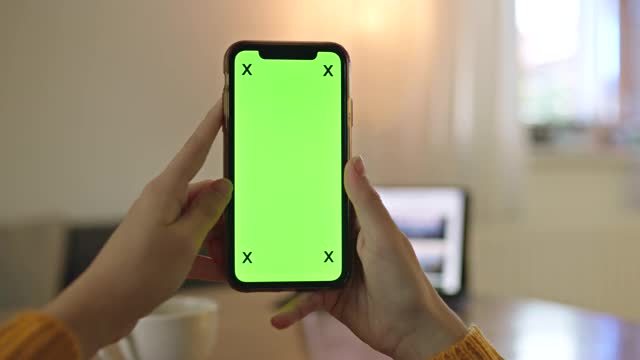在家里拿着色度键的绿屏智能手机的人难以辨认视频素材
