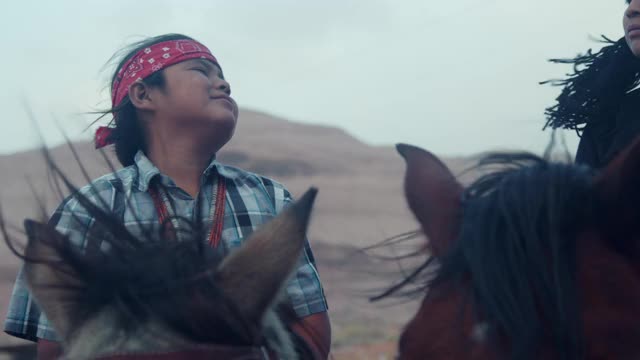 纳瓦霍小男孩骑在马上，戴着头巾准备骑马视频素材