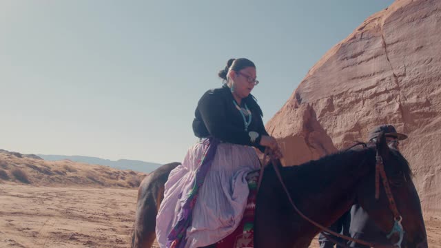 20多岁的纳瓦霍妇女在亚利桑那州北部纪念碑谷附近的家中骑马视频素材