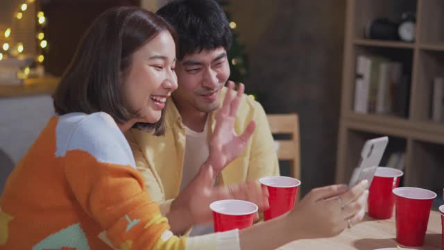 亚洲情侣喜欢一边用笔记本电脑打视频电话，一边包装礼盒视频素材