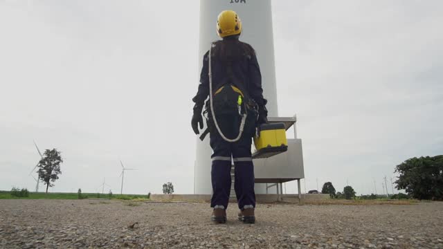 在泰国风电场，亚洲女工程师制服检查工程师准备和进度检查风力发电机的安全。视频下载