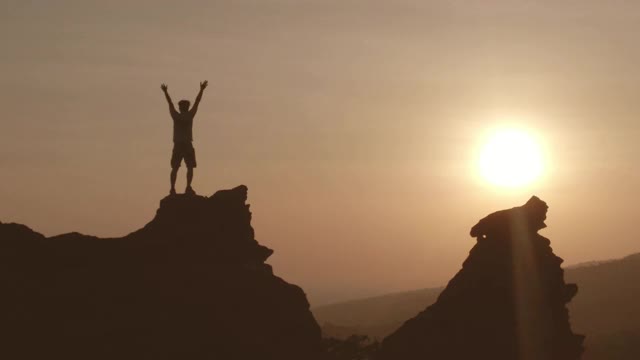 在日出日落的背景下，人在山顶举手视频下载