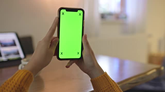 在家里拿着色度键绿屏智能手机的女人难以辨认视频素材