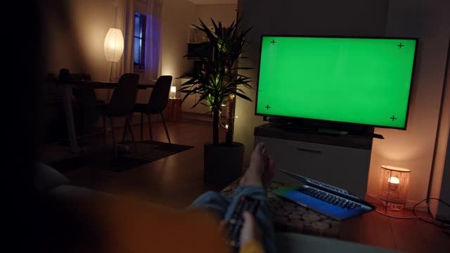 一个陌生的女人在彩色键绿色屏幕的电视上浏览频道视频下载