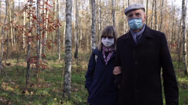 2019冠状病毒病大流行期间，一对老年夫妇在森林里散步视频素材
