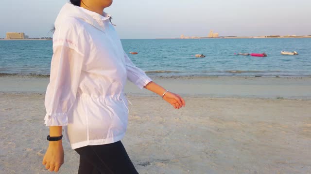 一个女人在海滩上边走边用智能手表视频素材
