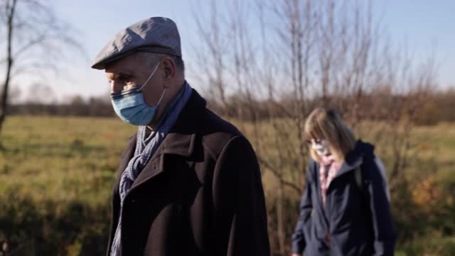 2019冠状病毒病大流行期间，在草地上散步的老年夫妇视频素材