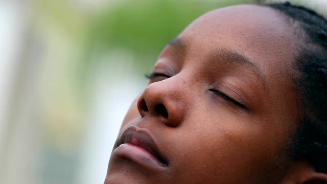 黑人少女睁开眼睛望着天空。非洲混血少女微笑着希望和信仰视频素材