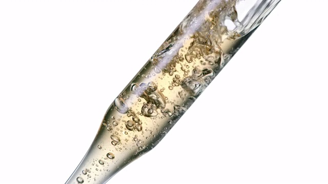 近距离和超级缓慢的运动，轻金色的水气泡倾倒在一个清晰的移液管放置在白色背景对角线视频下载