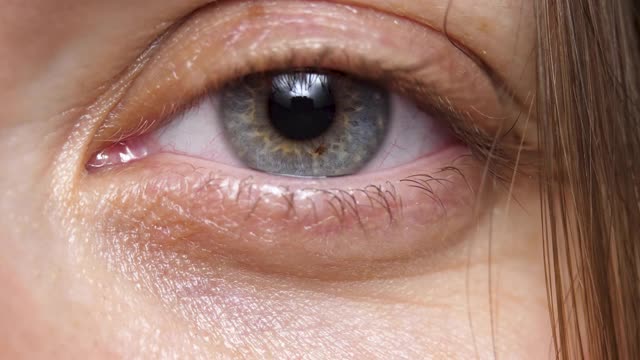 女人的眼睛，瞳孔周围的灰色和蓝色区域是虹膜视频素材