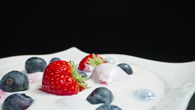 近距离拍摄的混合水果碗与草莓蓝莓倒牛奶和酸奶视频素材