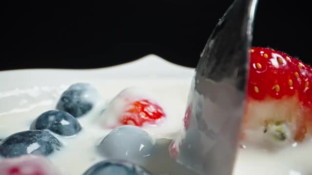 近距离拍摄的酸奶水果碗与草莓和蓝莓混合勺子由一个男性的手视频素材