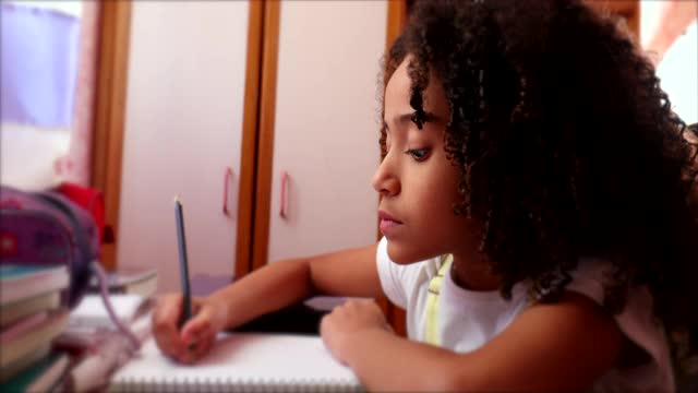 多民族的小女孩用钢笔写笔记。孩子在家里做作业视频素材