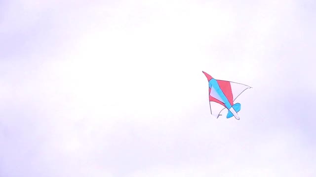 蓝天下，一只带着表情符号的彩色风筝悬在空中视频下载