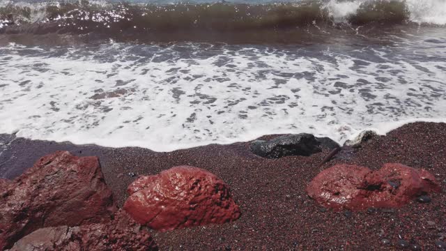 圣托里尼岛的红色海滩，海浪拍打岩石的慢镜头视频素材