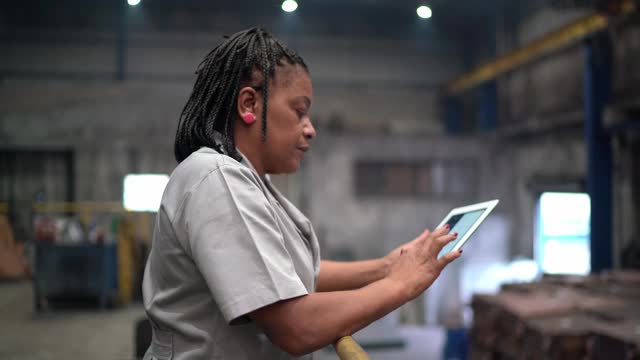 一个成熟的女人在工厂里用着平板电脑冥思苦想视频素材