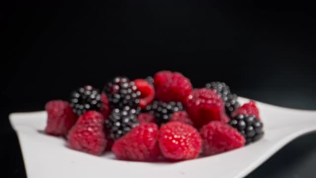 移动近距离拍摄的新鲜树莓和黑莓倒在酸奶和牛奶在黑色的背景视频素材