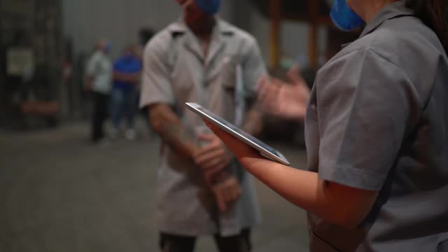金属工业工人在工厂里谈论和使用数字平板电脑视频素材