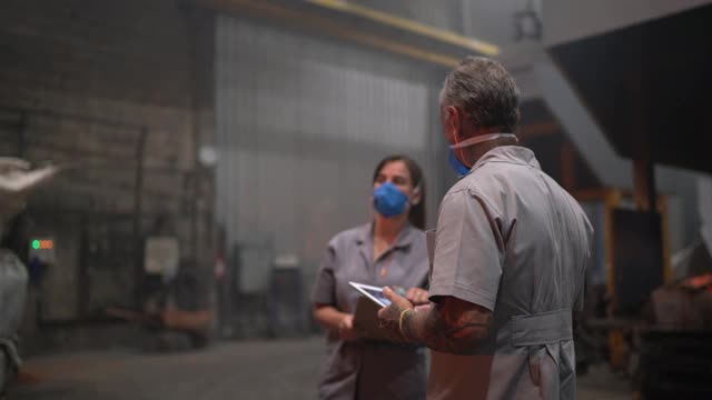 金属工业工人在工厂里谈论和使用数字平板电脑视频素材