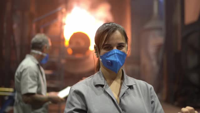 一个在工厂工作的年轻女人的肖像，站在火炉前视频素材