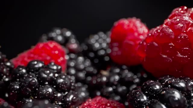 移动近距离拍摄通过新鲜的树莓和黑莓与黑色的背景视频素材