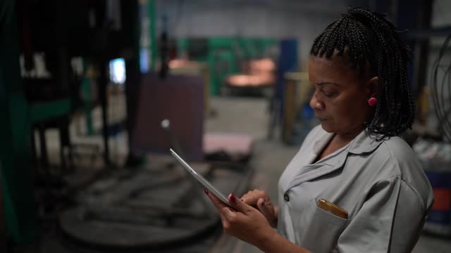 一个成熟的女人在工厂用平板电脑工作的肖像视频下载