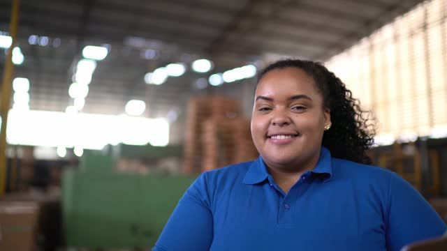 一个快乐的年轻女人在工厂/配送仓库工作的肖像视频素材