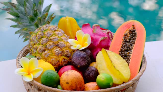 热带异国情调的篮子。木桌上的水果和游泳池的背景视频下载