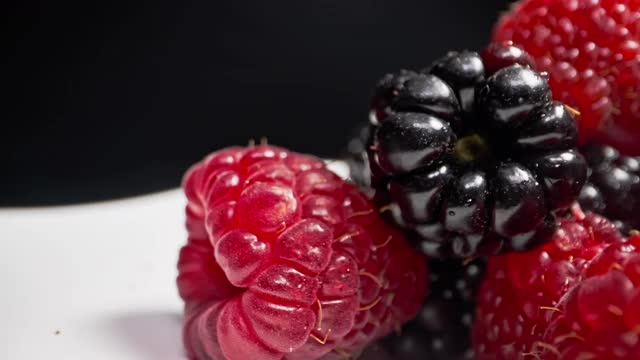 移动近距离拍摄通过新鲜的树莓和黑莓与黑色的背景视频素材