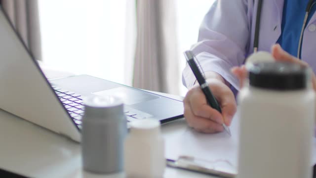 医生在病历上写字，在笔记本电脑上打字视频素材