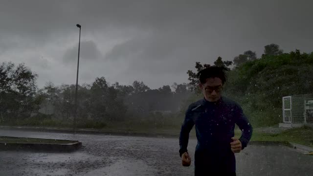 一个穿着运动服的亚洲华人运动员在雨中在街道上慢跑视频下载