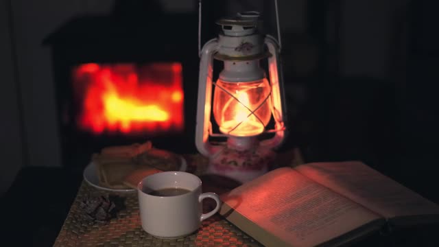 在燃烧的壁炉旁的一盏kerassin灯下，在一个舒适的家庭气氛中品尝着茶和饼干。视频素材