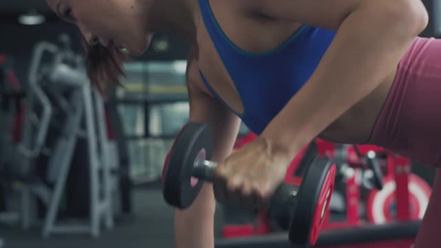 美丽的年轻女子在健身房举重，慢镜头。视频素材