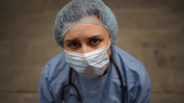 拖出:疲惫的女护士或医生坐在医院附近，低下头视频素材