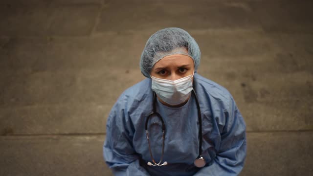精疲力竭的女外科医生在医院附近摔倒在地视频素材