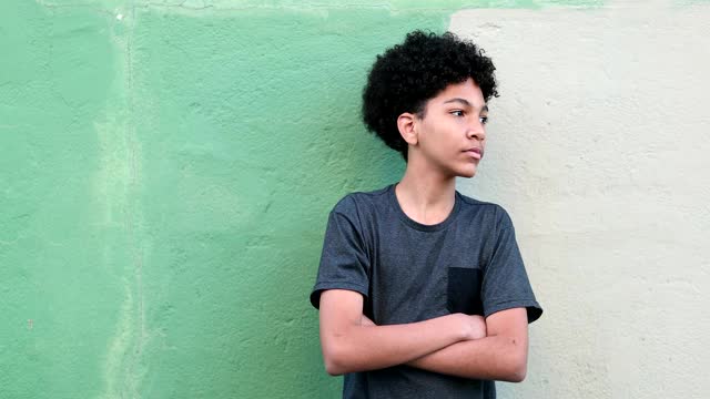 一个小男孩双手交叉站在外面观察。混合种族儿童黑人民族微笑视频素材