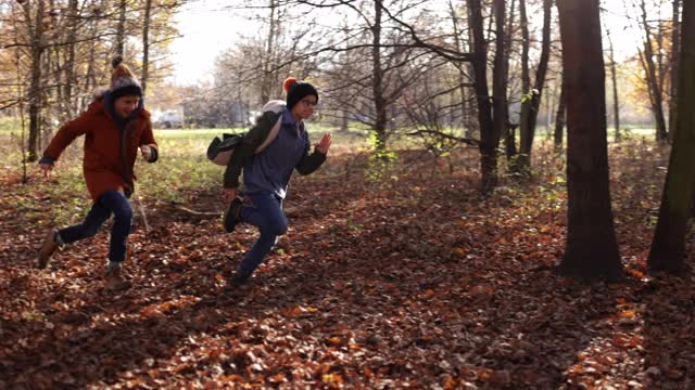 两个男孩在秋天的森林里奔跑视频下载