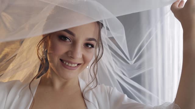 新娘在面纱和丝绸长袍下的闺房礼服。婚礼仪式前的清晨准备视频素材