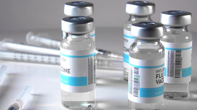 关闭流感疫苗10ml瓶，无菌透明小瓶，1ml无菌注射器在清晰的背景下旋转。视频下载