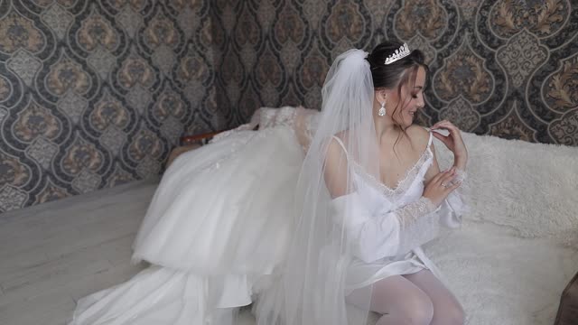 新娘穿着白色的闺房礼服，面纱和丝绸长袍。婚礼仪式前的清晨准备视频素材