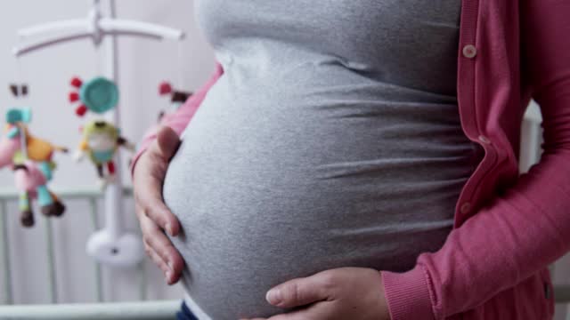 一名孕妇在婴儿室爱抚着自己的肚子。视频素材