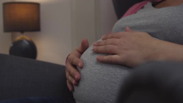 孕妇在晚上爱抚她的肚子。视频素材