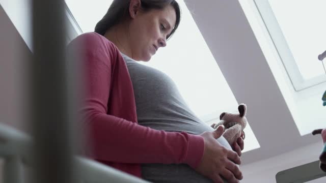 一名孕妇在婴儿室爱抚着自己的肚子。视频素材