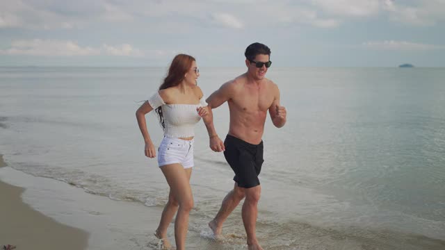 情侣跑步享受生活玩和自由沙滩日落，有吸引力的男人和女人一起旅行与约会浪漫的人的生活方式。4 k UHD。视频素材