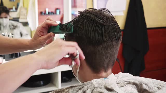 新冠肺炎疫情下发型师为青少年男孩理发的实时视频视频素材
