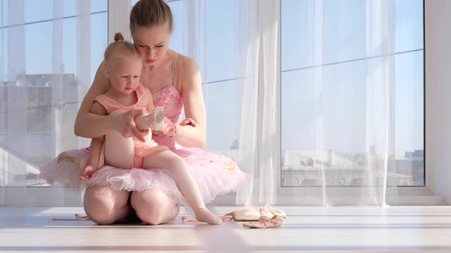 漂亮的芭蕾舞演员教她的小女儿如何系芭蕾舞鞋视频素材