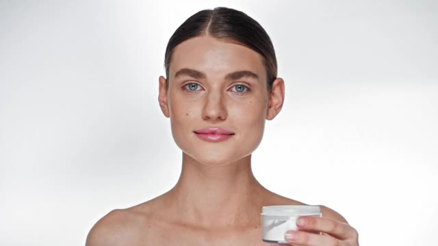 年轻的成年女性用化妆刷在白色的脸上涂高光视频下载