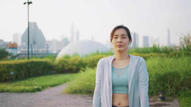 年轻的亚洲女子在户外跑步前做伸展运动视频素材