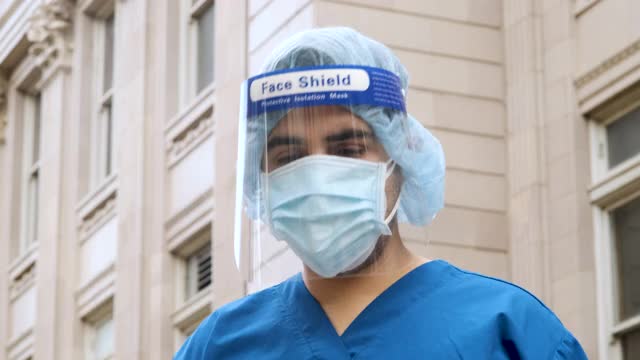 年轻的医护人员在一天漫长的工作后摘下防护口罩和面罩视频素材
