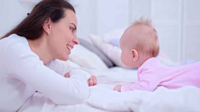 肖像中，一位年轻美丽的妈妈正在和她的宝贝女儿说话，抚摸着宝宝的脸微笑着。母婴沟通，家庭价值观。4 k, ProRes视频素材